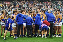 Australian rules footballers in a team huddle