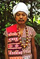 A Karbi man of West Karbi Anglong in traditional attire, wearing a Poho (white turban), a choi-hongthor (woven jacket), a lek paikom (gold-plated necklace) and another poho on his right shoulder.