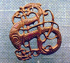 Filigrana vikinga en bronce del siglo XI. La principal aportación de la influencia bárbara al arte altomedieval fue su particular enfoque del problema de la ornamentación, que dejó de ser naturalista para pasar a ser muy geométrica, casi heráldica; motivos trenzados y "en tenaza", la geometrización de motivos anteriores, como las vides pobladas de aves o la misma cruz, desde la cristianización de los bárbaros fueron interpretados de forma totalmente innovadora.[7]​