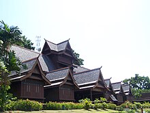 Large intricate wooden house facing right, forest in background