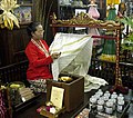 A Batik Tulis maker applying melted wax following pattern on fabric using canting, Yogyakarta (city), Indonesia.