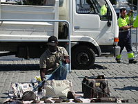 Street vendor with a string and sheet set-up allowing for quick departure. Immigrants are often vendors and sometimes sell counterfeit goods