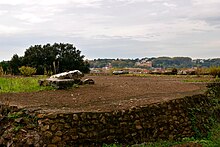 Photograph of an earthen terrace, held up by a retaining wall.