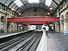 The interior of a building with a rounded ceiling and a railway track running down the middle of the corridor flanked by brick arches