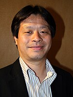 A 42-year-old Japanese man with trimmed black hair, smiling directly at the camera.