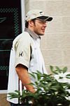 Jacques Villeneuve wearing spectacles and a white baseball cap