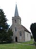 A small stone church with a spire in front