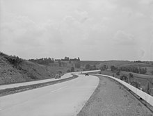 Black-and-white photo of a four-lane highway, with one car in each direction