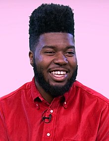 Khalid smiling while wearing a red shirt