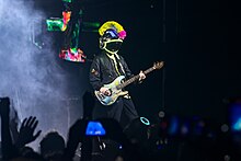 Berryman onstage with his bass, wearing a custom helmet