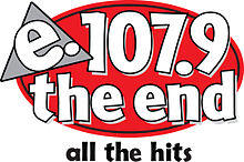 A red oval with a loose black outline. Atop it in the upper left is a gray triangle with a black outline and white lowercase letters "e." trimmed in black. On the rest of the oval, in white lowercase letters trimmed in black, is "107.9 the end" on two separate lines. Beneath is the slogan "all the hits" in black.