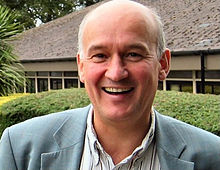 A photograph of Walach smiling in front of a building