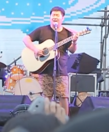 Song Dongye playing the guitar and singing during a musical performance