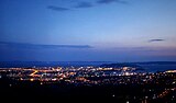 In view from the fortress towards Split at night, there is dark blue sky, and city lights below.