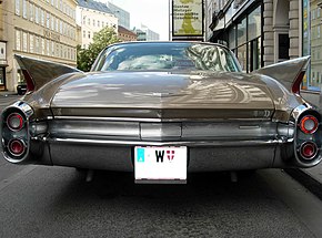 1960 Cadillac Coupe Deville, встроенные в «плавники» и снизу в «соплах» — красные задние фонари, работающие совместно, вверху в «соплах» — белые фонари заднего хода, обрамлённые красными отражателями