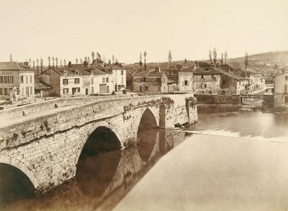 Black and white view of a three-arched bridge over a river, with a hilly town in the background.