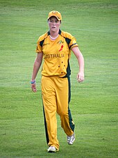 A female Australian cricketer, in a yellow uniform, wearing a yellow cap