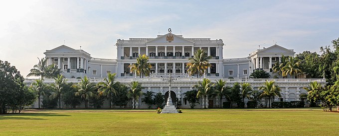 Three-story colonnaded facade with palm trees in front