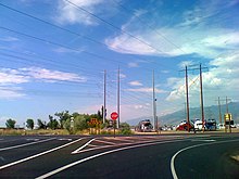 A two lane road with a separate turning lane, with a red octagonal stop sign in the middle.