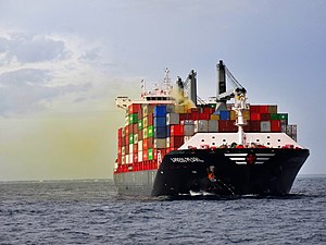 Cargo ship at sea with brownish fumes coming from a container amidships