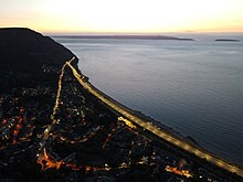 This view at sunset shows how the modern A55 Expressway bypasses the older road through the town centre before resuming the original route around the headland.