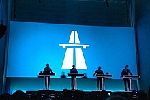 Four figured in shadow on a stage behind a screen projecting the autobahn album cover from the reissue behind them.