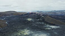 Cooled lava fields can be seen, whilst the Fagradalsfjall volcano erupts in the background