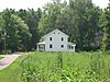 A white house sitting amid fields and woods