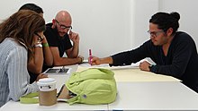 A group of writers gather at a desk to collaborate