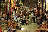 Goods overflow out of storefronts, leaving a narrow passageway where shoppers move about.