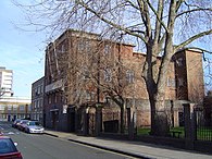 depicts an outside look at Kingsley Hall, a brick building, in London