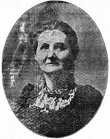 A newspaper image of a middle-aged white woman, in an oval frame.