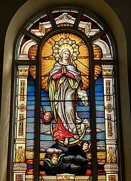 The coronated Blessed Virgin Mary in heaven depicted as the "woman clothed with the sun, with the moon under her feet, and on her head a crown of twelve stars" (Revelations 12:1). - stained glass window in St. Joseph's Basilica, California, USA, 1921.