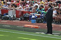 A coloured photograph of manager Rafael Benítez standing on the stadium touchline.