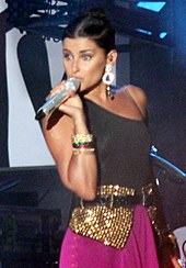 A woman in a black dress walking a red carpet.