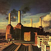 Picture of factories with tall chimneys pouring out black smoke. A large pig is seen floating in the sky above the factories.