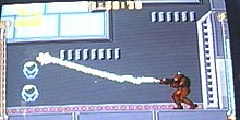 A video game screenshot of a person in a powered exoskeleton firing a beam.