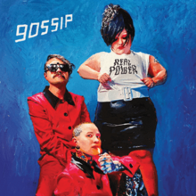 The three members of Gossip in front of a blue background; Beth Ditto stands wearing a shirt that says "Real Power", while Nathan Howdeshell and Hannah Billie are seated