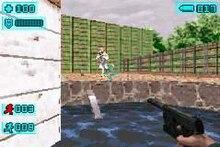 From the unseen protagonist's point of view, his handgun is pointed at an enemy soldier standing about thirty feet away. He stands in a pool of water while the enemy is on a slightly elevated stone floor. The outdoor area is bordered by a wooden fence, over which trees and the overcast sky are visible. Features such as ammunition remaining, health, and lives adorn the screen, all in a stylized science fiction-esque font.