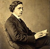 Photographic portrait of Charles Lutwidge Dodgson (Lewis Carroll), seated and holding a book