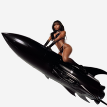 A scantily clad Normani riding a shiny black phallic rocket ship against a white backdrop.